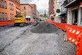 excavator on a gravel road during road work on the street between tall buildings