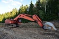Excavator during groundwork at forest area for construction new road. Orange backhoe on road work, land clearing, grading,