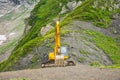 Excavator heavy equipment in mountains on steep range slopes