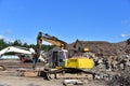 Excavator with hydraulic breaker hammer for destruction of concrete and hard rock at landfill. Disposal of construction waste.