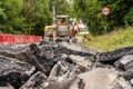 Excavator with hydraulic jack hammer  breaking asphalt in preparation for drainage works close up Royalty Free Stock Photo