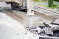 Excavator with hydraulic jack hammer breaking asphalt in preparation for drainage works close up Royalty Free Stock Photo