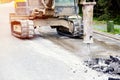 Excavator with hydraulic jack hammer  breaking asphalt in preparation for drainage works close up Royalty Free Stock Photo