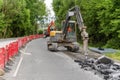 Excavator with hydraulic jack hammer  breaking asphalt in preparation for drainage works close up and selective focus Royalty Free Stock Photo