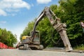 Excavator with hydraulic jack hammer breaking asphalt in preparation for drainage works close up and selective focus