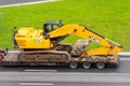 Excavator JCB Truck trailer loaded onto cargo platformon city highway. Russia, Saint-Petersburg. 18 may 2020