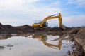 Excavator at lake in the quarry on sunset background. Backhoe during earthmoving work at open-pit mining. Royalty Free Stock Photo