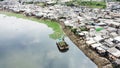 Excavator on lake with slum houses background