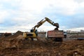 Excavator load the sand to the heavy dump truck on construction site. Excavators and dozers digs the ground for the foundation Royalty Free Stock Photo