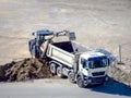 Excavator loading dumper truck. Excavator loading dumper truck tipper in sand pit over blue sky Royalty Free Stock Photo