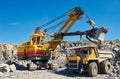 Excavator loading granite or ore into dump truck at opencast Royalty Free Stock Photo