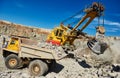 Excavator loading granite or ore into dump truck at opencast Royalty Free Stock Photo