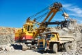 Excavator loading granite or ore into dump truck at opencast Royalty Free Stock Photo