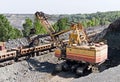 Excavator loading iron ore into goods wagon. Iron ore opencast mine