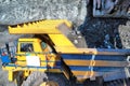 Excavator loading iron ore into heavy dump trucks