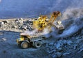 Excavator loading iron ore into heavy dump trucks Royalty Free Stock Photo