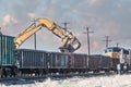 Excavator loading old railroad ties in open boxcars Royalty Free Stock Photo