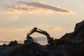 Excavator loading soil into a dump truck at dusk during road construction, creating a dramatic silhouette against the evening sky Royalty Free Stock Photo