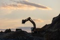 Excavator loading soil into a dump truck at dusk during road construction, creating a dramatic silhouette against the evening sky Royalty Free Stock Photo