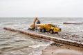 Excavator loading a truck stones on the beach