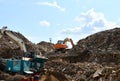 Excavator loads construction waste into reinforced concrete mobile shredder for crushing, recycling of construction mixed waste.