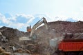 Excavator loads construction waste into reinforced concrete mobile shredder for crushing, recycling of construction mixed waste.