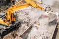 Excavator loads construction waste into truck for removal from construction site. Demolition of dilapidated housing for Royalty Free Stock Photo