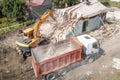 Excavator loads construction waste into truck for removal from construction site. Demolition of dilapidated housing for Royalty Free Stock Photo