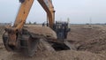 The excavator loads the sand to the heavy dump truck on the construction site. Excavators and dozers dig the ground for the