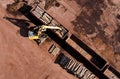 Excavator with log grab crane unloads timber from freight car. Crane with claw loads logs onto log train for lumber mill. Illegal Royalty Free Stock Photo