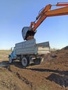 Excavator machine loading soil into truck body. Modern loading equipment