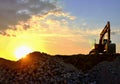 Excavator in a mining quarry at sunset. Crushing concrete and gravel construction site or open pit Royalty Free Stock Photo