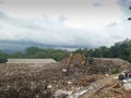 an excavator is moving a pile of garbage, photo taken at the landfill in Purworejo district