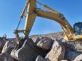 Excavator is moving a rock boulders during road construction on the rocky soils Royalty Free Stock Photo