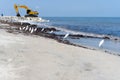 Excavator moving rock at the coast line