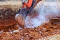 Excavator digs into soil at construction site during digging trench Royalty Free Stock Photo