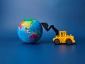 Excavator pushing earth globe on blue background