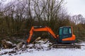 Excavator raking the ground on a snow-covered construction site