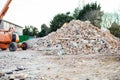 Excavator removes construction waste after building demolition. Building rubble, bricks, stones. Junk, Garbage piled up Royalty Free Stock Photo