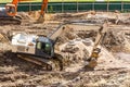 Excavator on road dug fresh soil road. Construction of a roadbed in a residential area