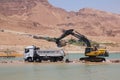 Excavator scooping soil of the Dead Sea for extraction of minerals. Israel