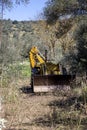 The excavator single-bucket parked by the road in the olive grove