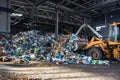 Excavator stacks trash in big pile at sorting modern waste recycling processing plant. Separate and sorting garbage collection.