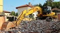 Excavator, on top of a pile of rubble, during a redevelopment building urban renovation