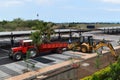 Excavator and truck working together in landscaping project. Palm trees to be planted to bring some green to a parking lot.