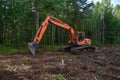 Excavator UMG E180C clearing forest for new development. Orange Backhoe modified for forestry work. Tracked heavy power machinery