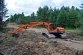 Excavator UMG E180C clearing forest for new development. Orange Backhoe modified for forestry work. Tracked heavy power machinery