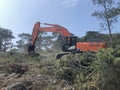 Excavator uproots stumps of cutted trees in the coniferous highland forest Royalty Free Stock Photo