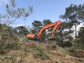 Excavator uproots stumps of cutted trees in the coniferous highland forest Royalty Free Stock Photo