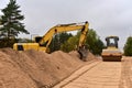 Excavator and Vibro Roller Soil Compactor at road construction and bridge projects in forest area. Heavy machinery for road work.